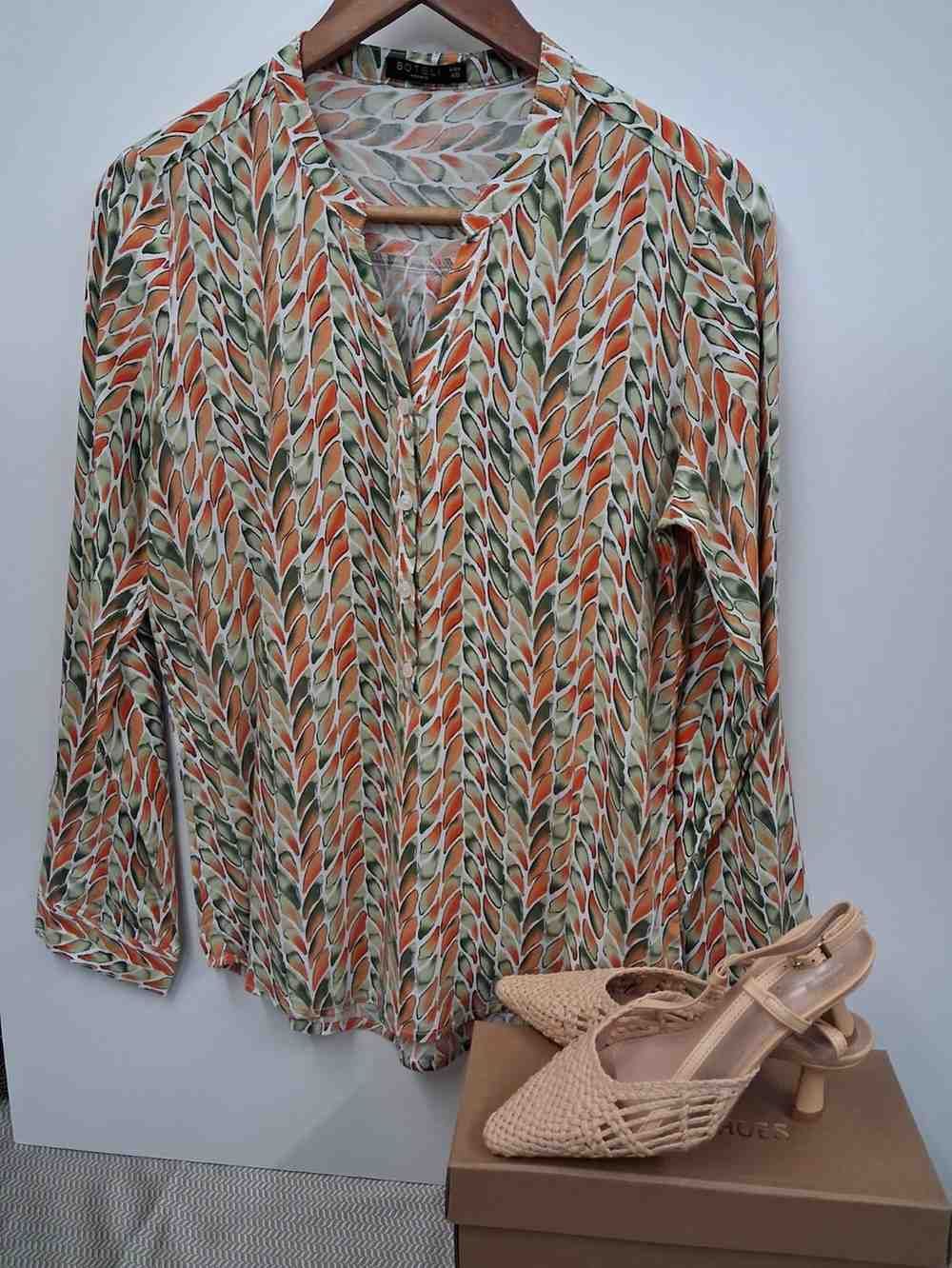 Una túnica estampada de manga larga en una percha junto a un par de zapatos