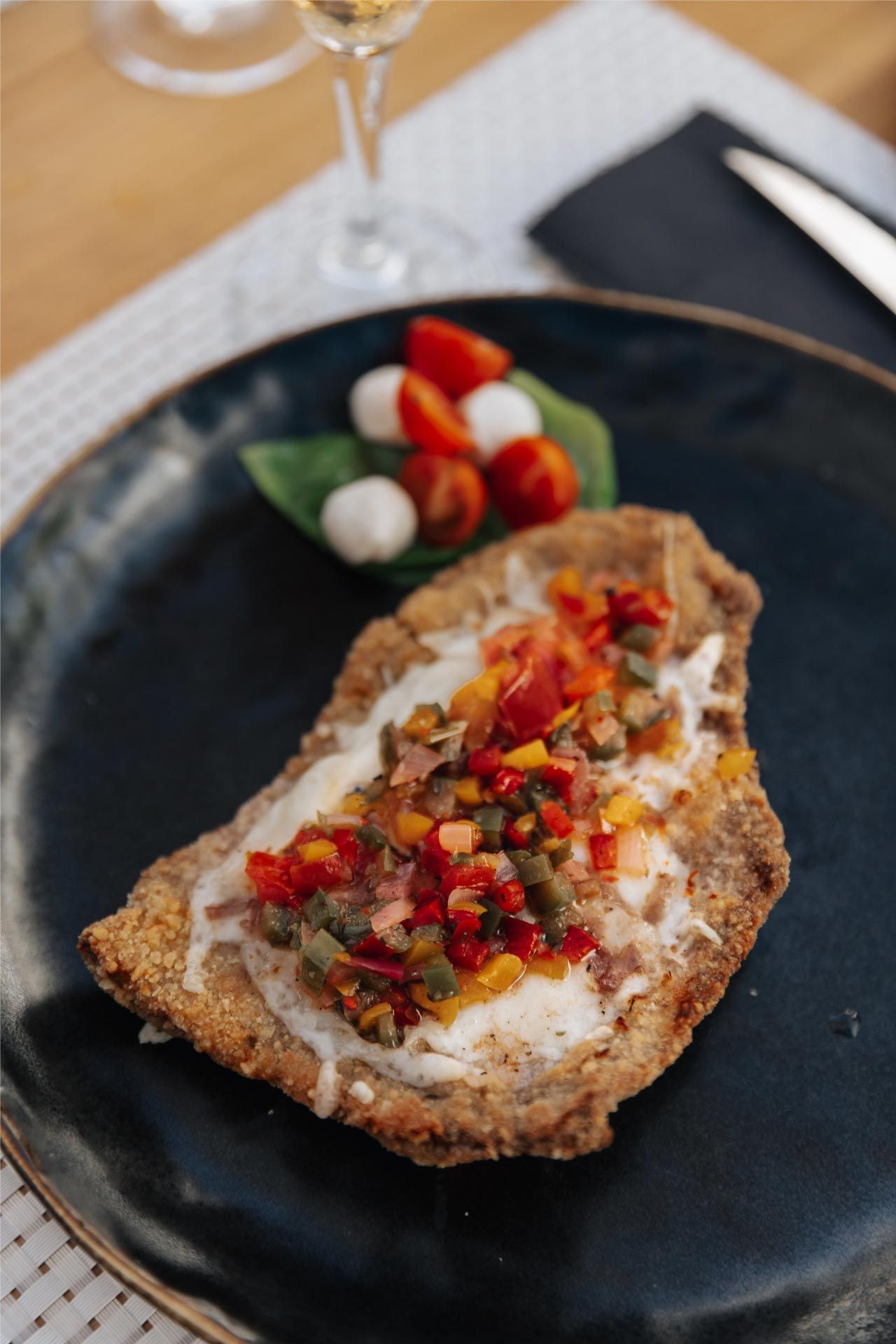 Carne empanizada con tomates picados, alcaparras y mozzarella; tomates cherry y albahaca.