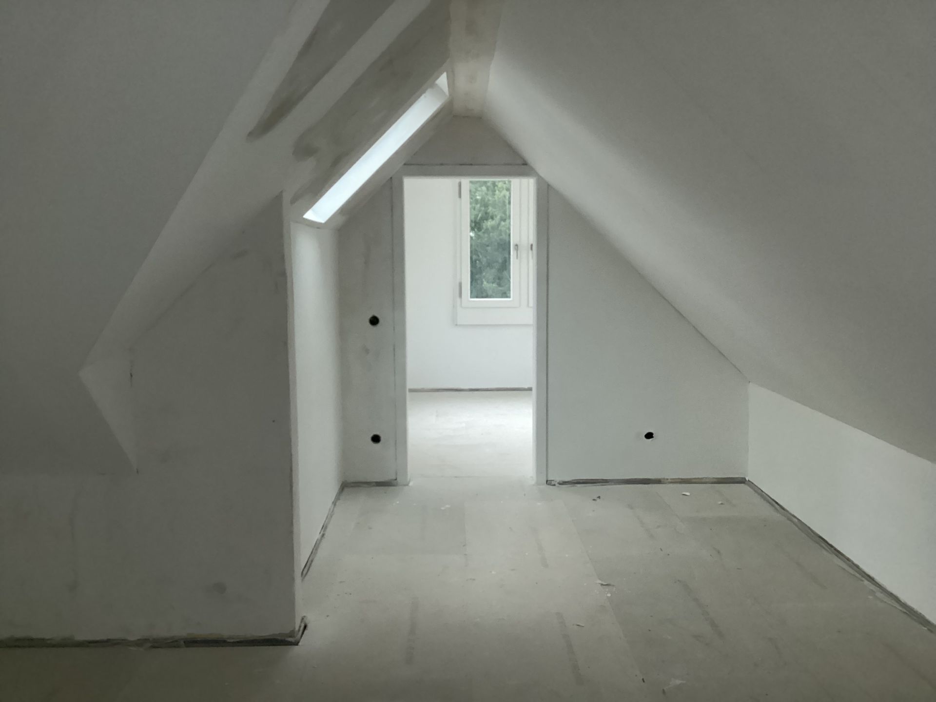 Ein leerer Dachboden mit weißen Wänden und einem Fenster