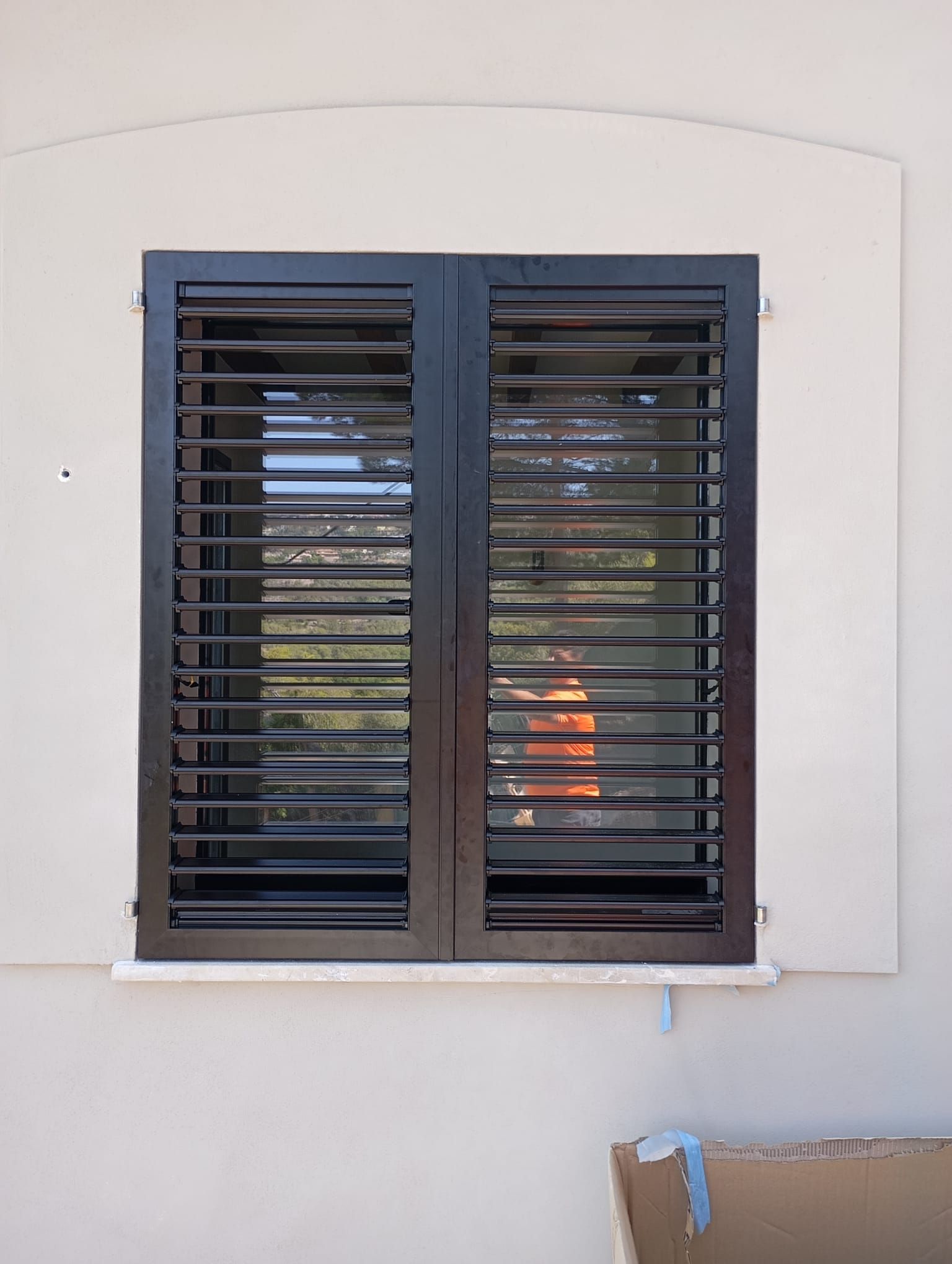 Contraventanas negras en una ventana con borde beige.
