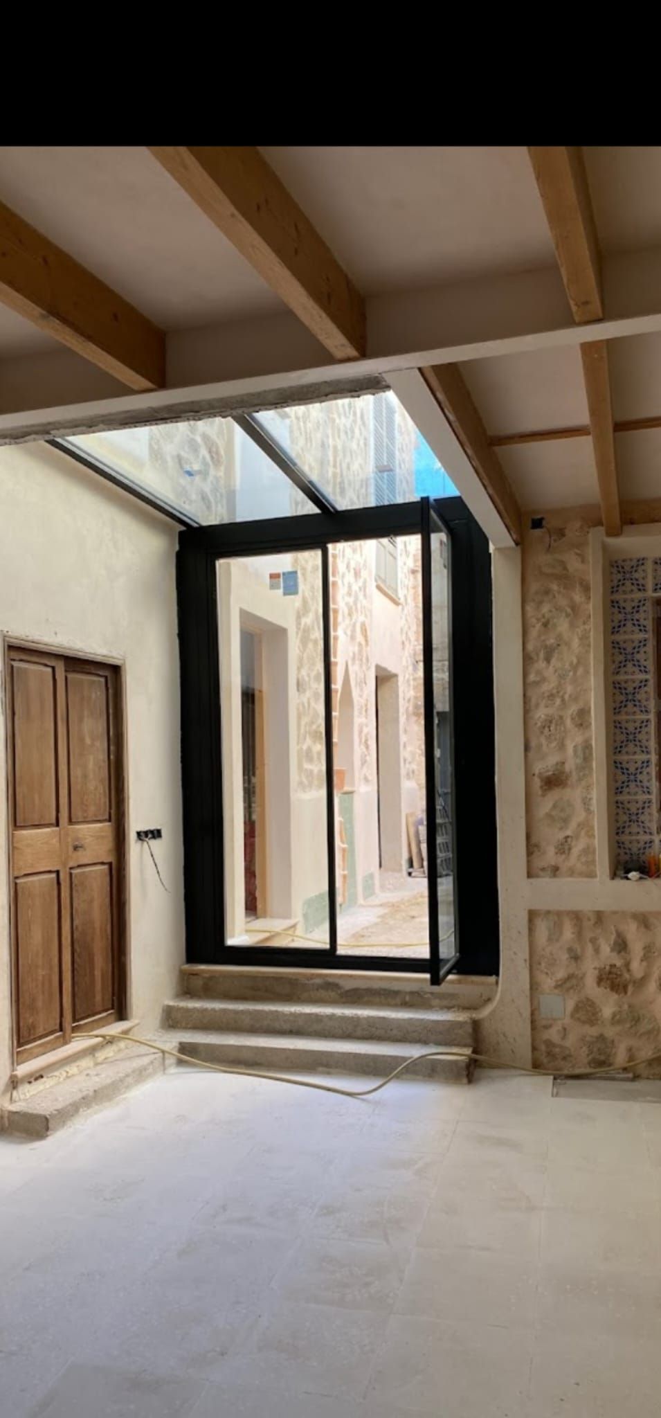 Vista interior de un edificio con paredes de piedra, vigas de madera, un tragaluz de vidrio .