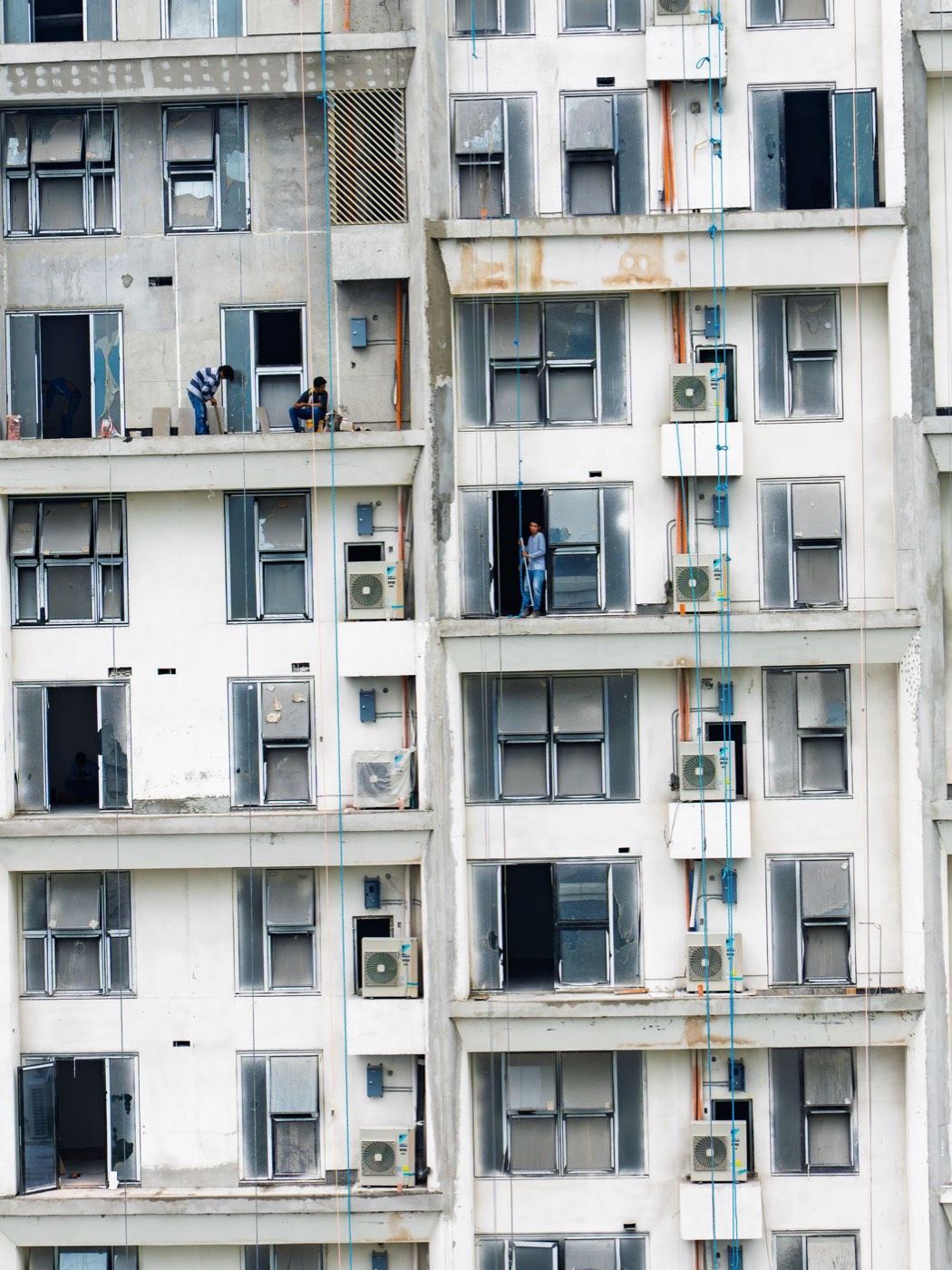 Fassade eines Mehrfamilienhauses mit vielen Fenstern, Balkonen und wandmontierten Klimaanlagen