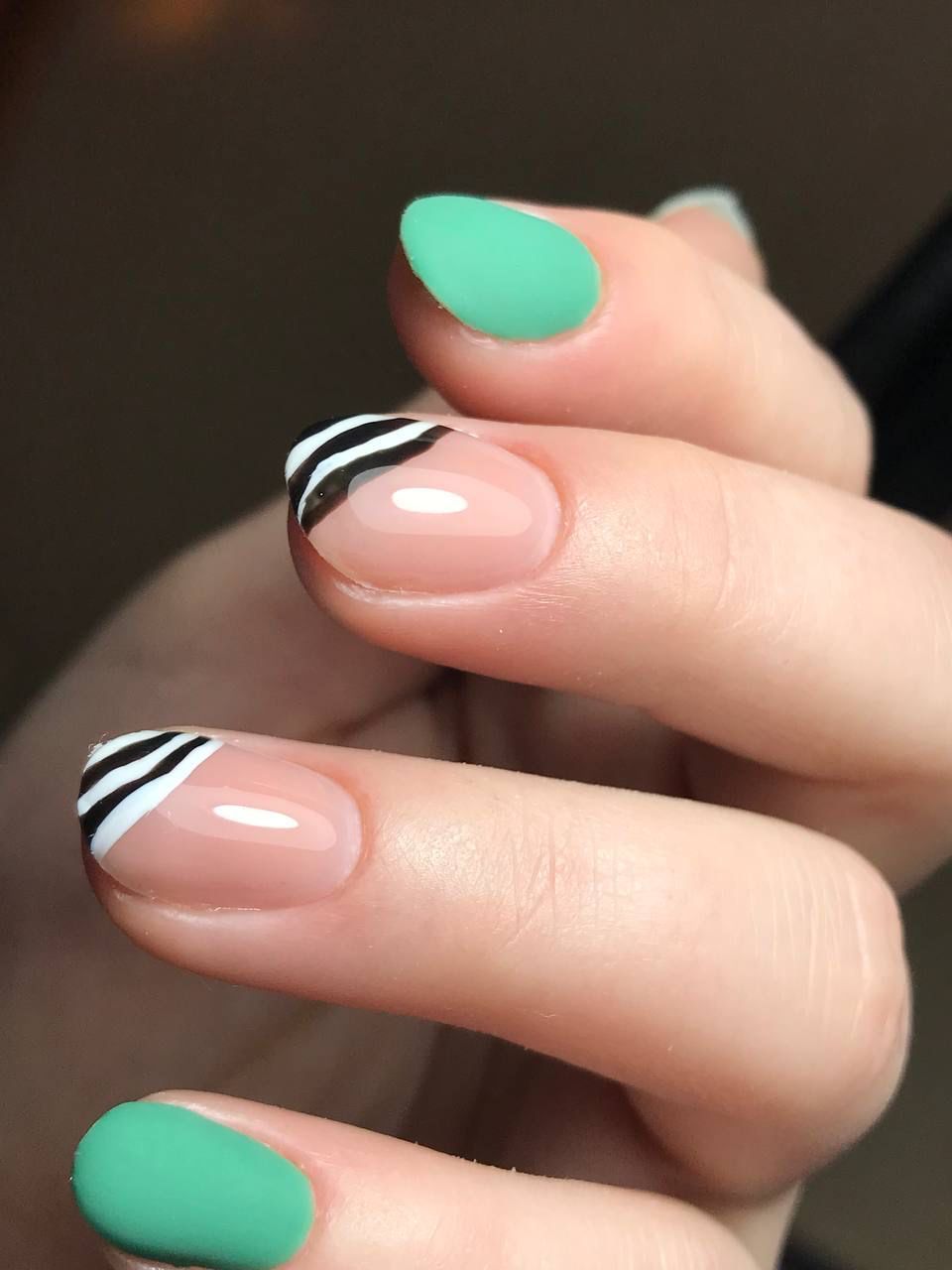 Eine Nahaufnahme der Nägel einer Frau mit grünen und schwarzen Streifen