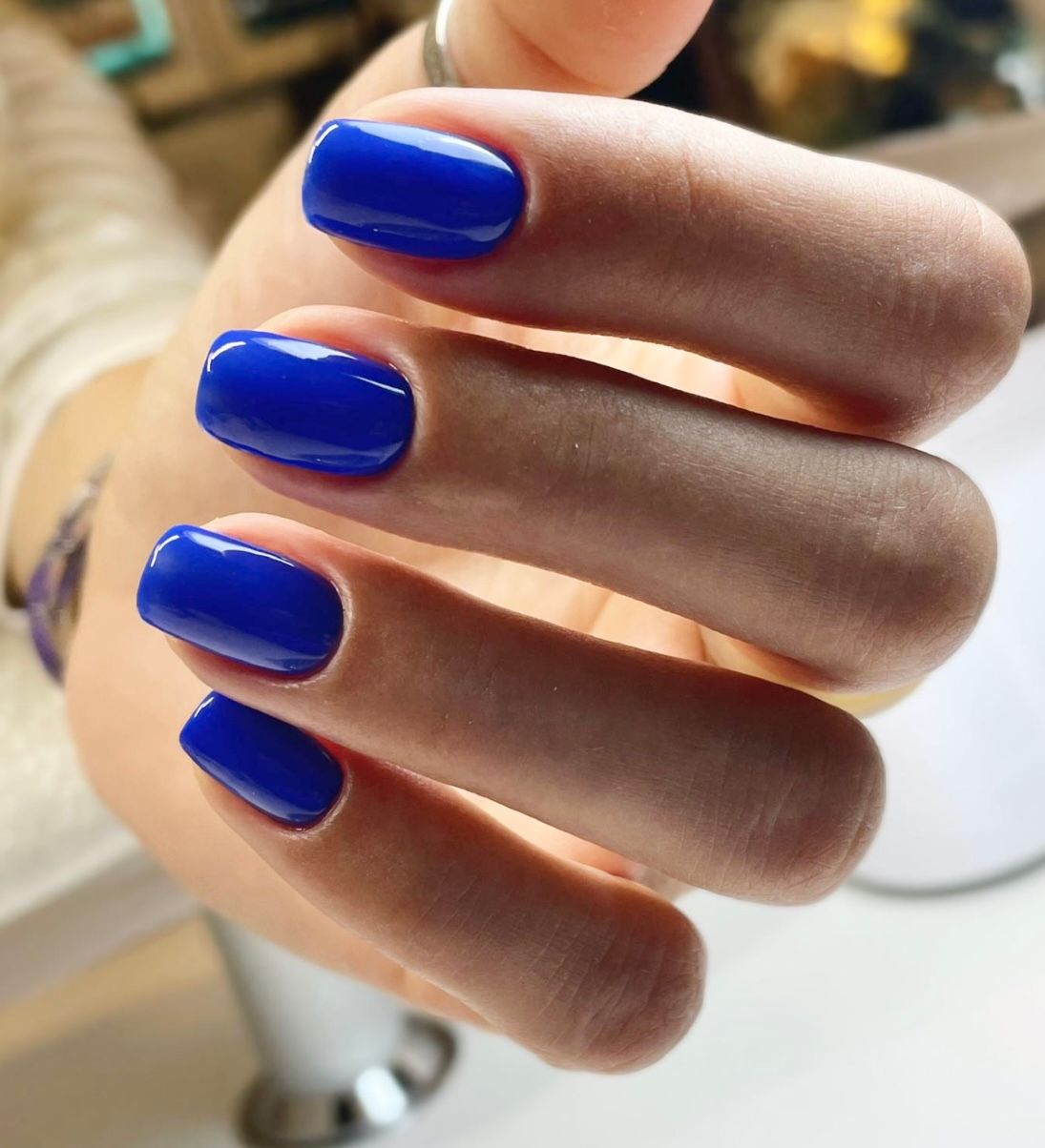 Eine Nahaufnahme einer Frauenhand mit blauen Nägeln