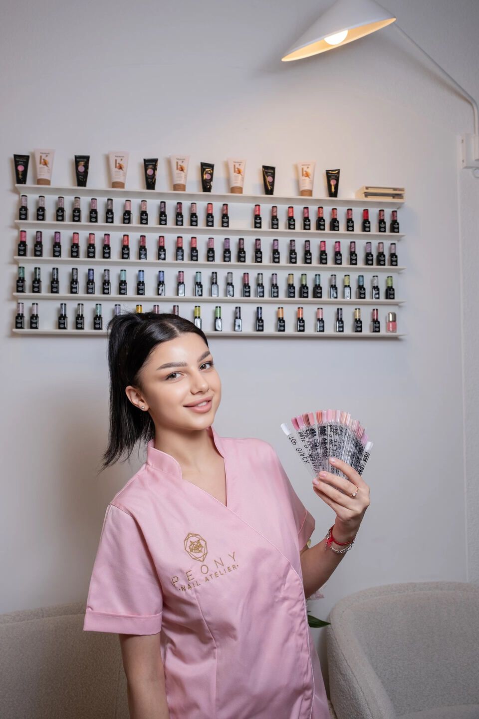 Eine Frau in einer rosa Uniform hält einen Haufen Nagellack in der Hand.