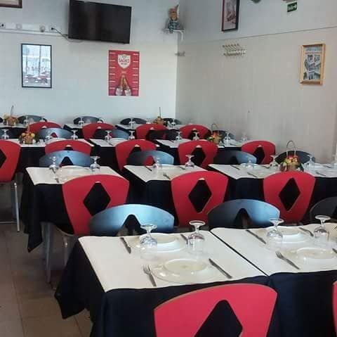 Um restaurante cheio de mesas e cadeiras com pratos e copos sobre elas