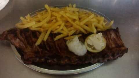 Um prato de costelas e batatas fritas sobre uma mesa.