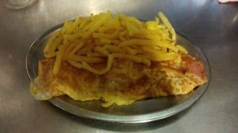 Um prato de comida com batatas fritas e um pedaço de carne sobre uma mesa.