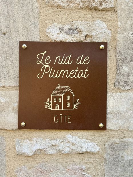 Plaque Le Nid de Plumetot sur la façade en pierre du gîte