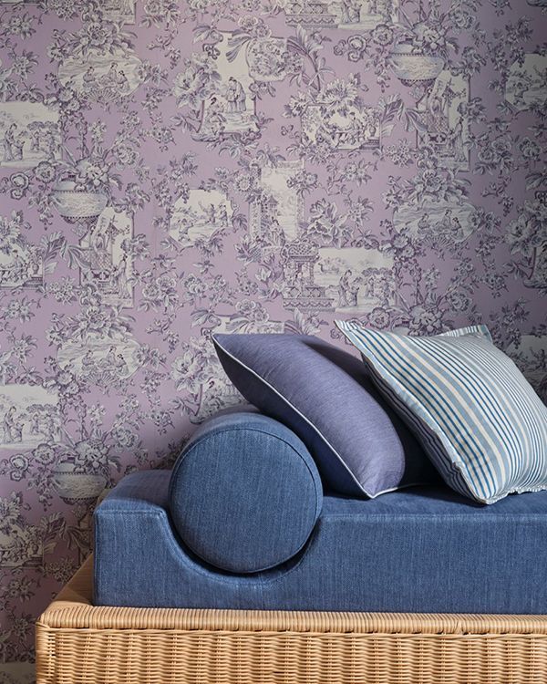 Blaues Tagesbett mit Kissen vor lavendelfarbener Toile-Tapete.