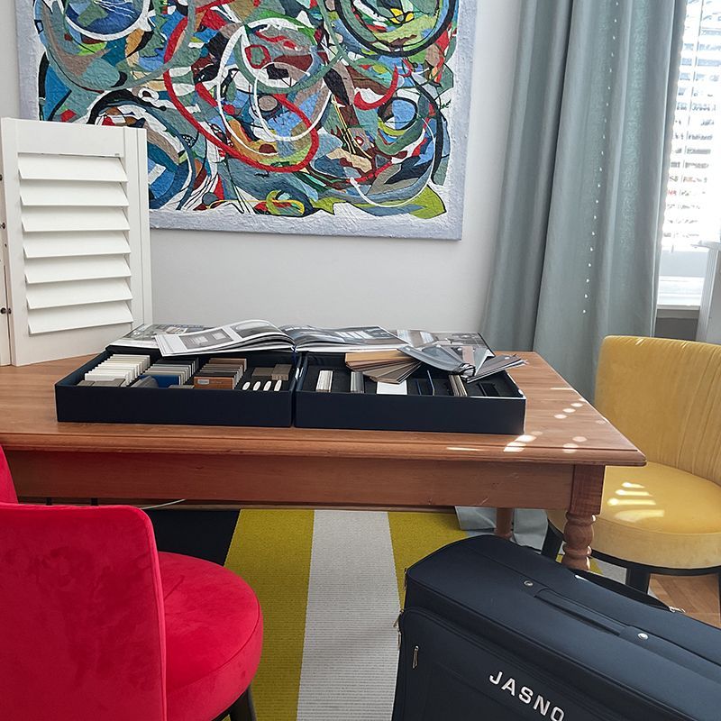 Innenarchitektur-Setup: Muster auf einem Holztisch mit einem bunten Teppich, Stühlen und abstrakten Kunstwerken.