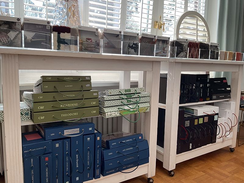 Weiße Tische mit Stoffmustern und Musterbüchern in einem Ausstellungsraum.