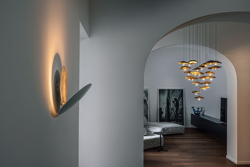 Moderner Flur mit Wandleuchter, gewölbter Tür und Kronleuchter.