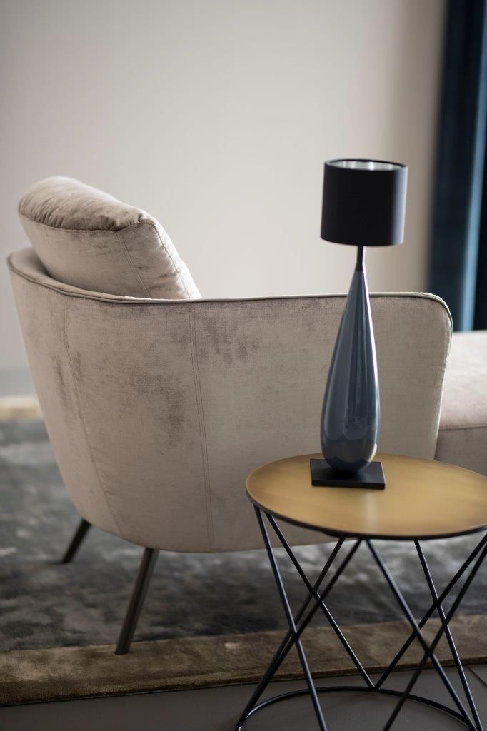 Beiger Sessel mit Beistelltisch und blauer Lampe.