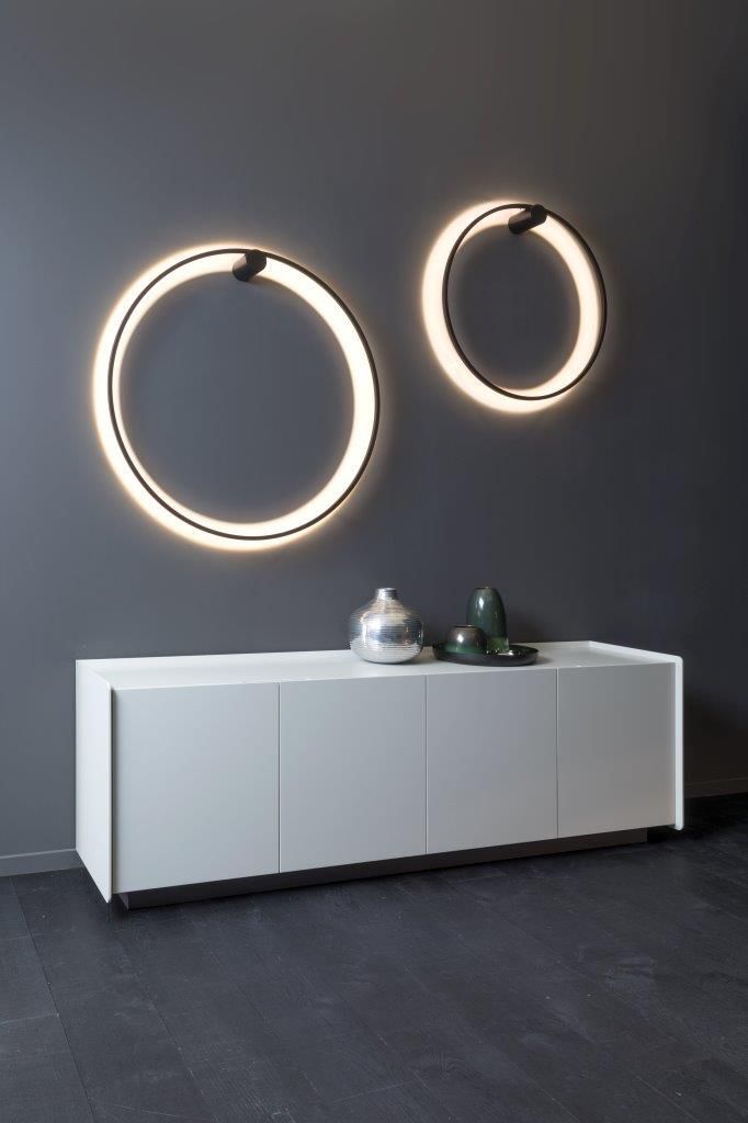 Zwei beleuchtete Ringlichter über einem weißen Schrank mit dekorativen Vasen vor einer dunkelgrauen Wand.