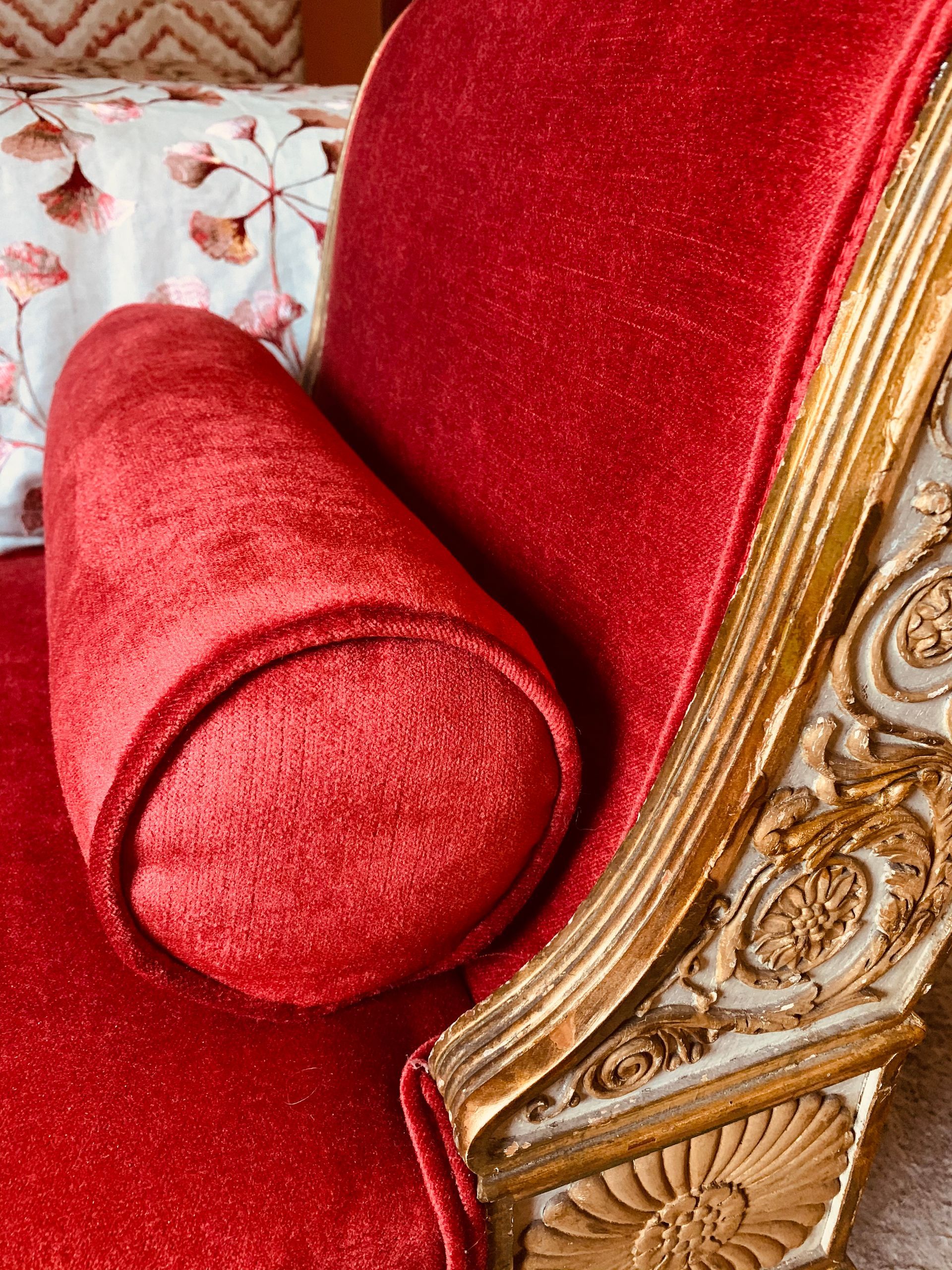 Roter Polsterstuhl mit dekorativer Armlehne aus Holz und Goldbesatz.
