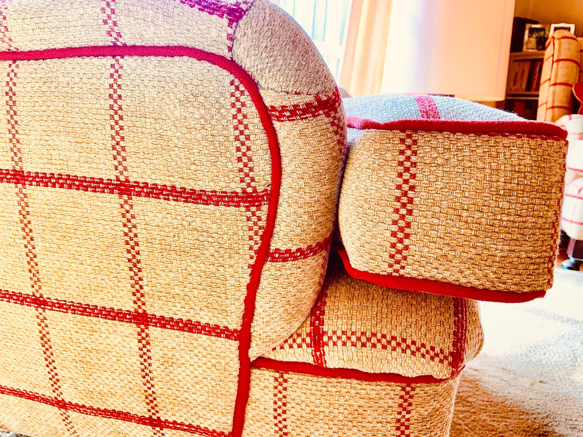 Beiger Sessel mit rotem Karomuster und Besatz in einem sonnendurchfluteten Raum.