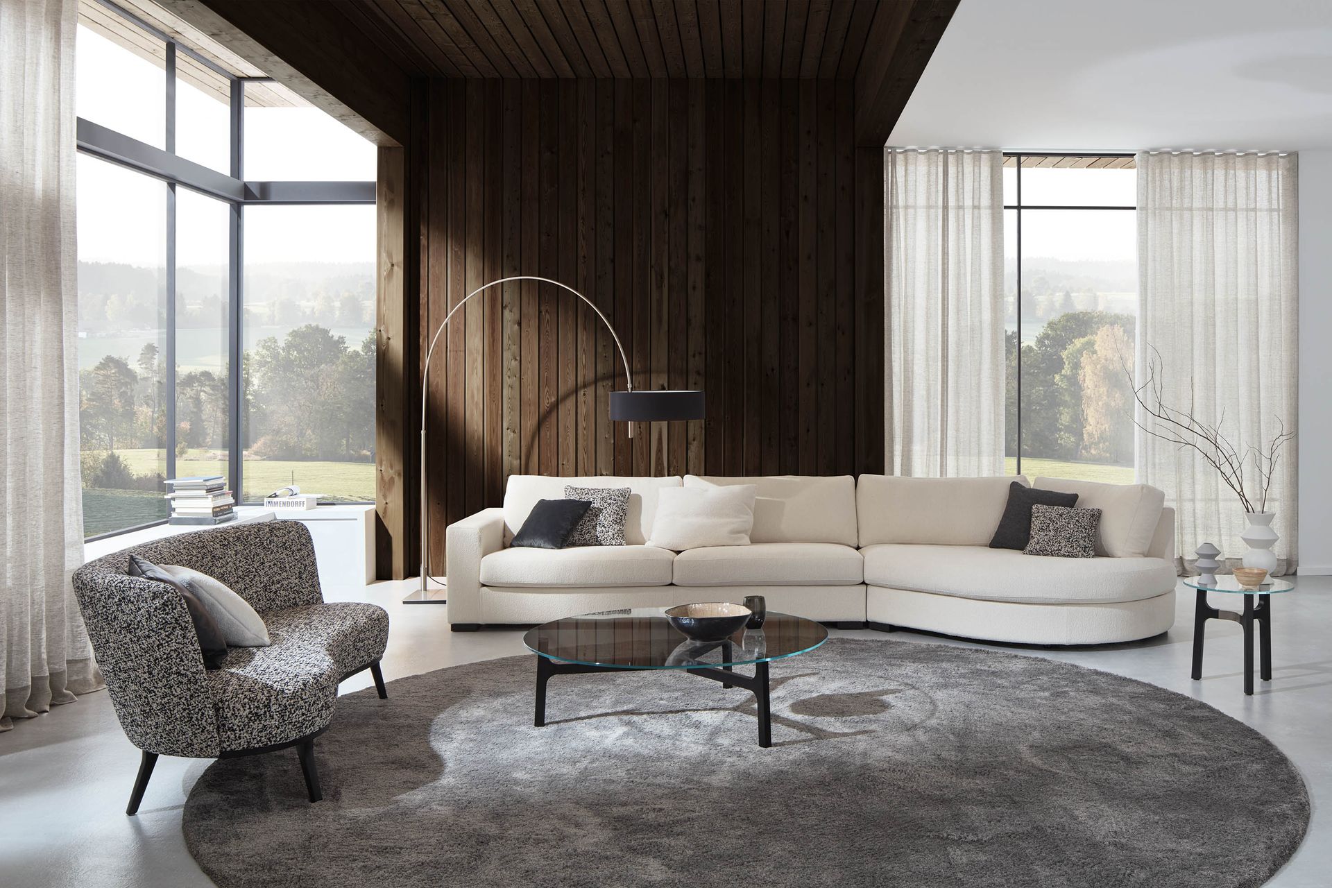 Modernes Wohnzimmer mit beigem Sofa, gemustertem Sessel und großem runden Teppich.