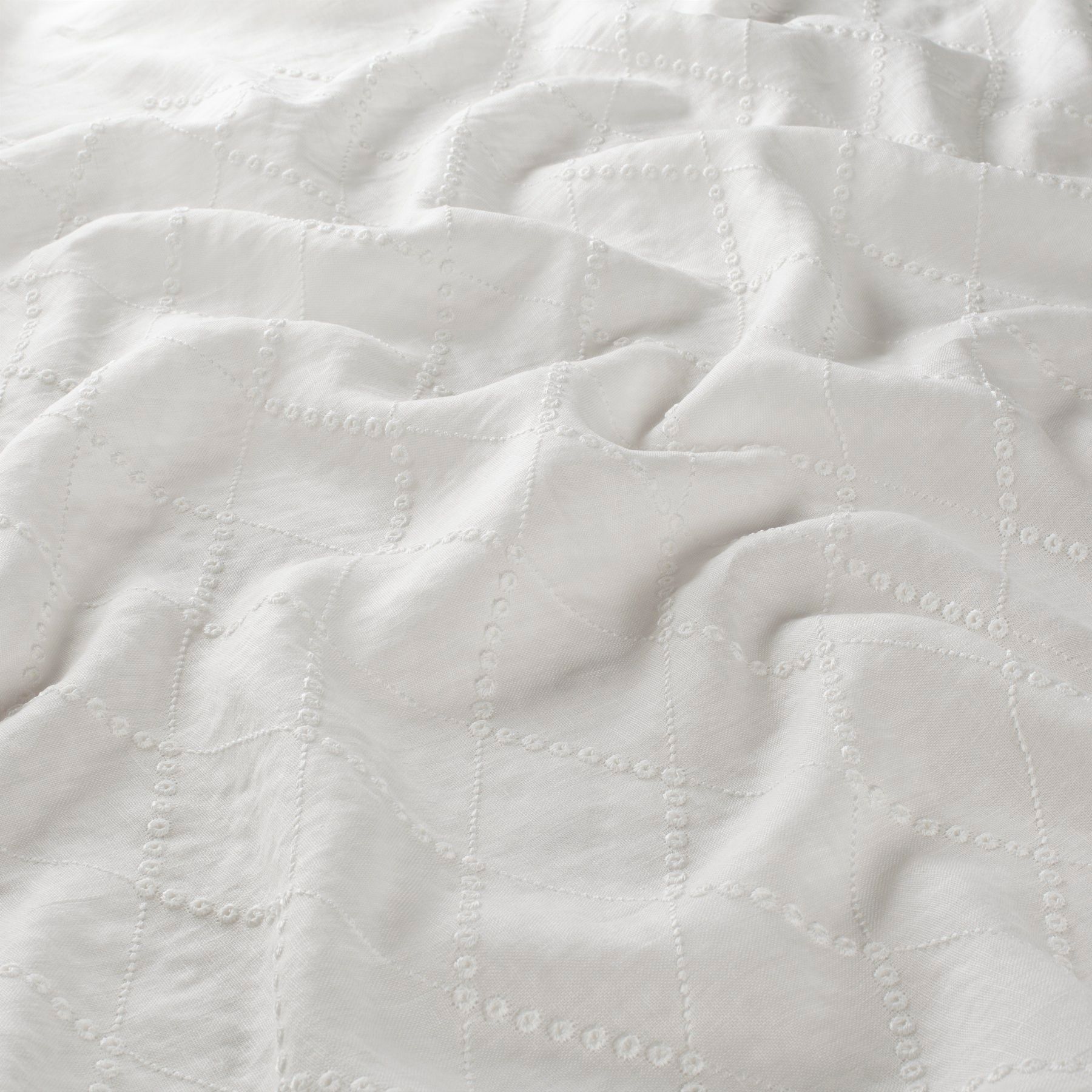 Weißer strukturierter Stoff mit gitterartigem Muster, drapiert und zerknittert.