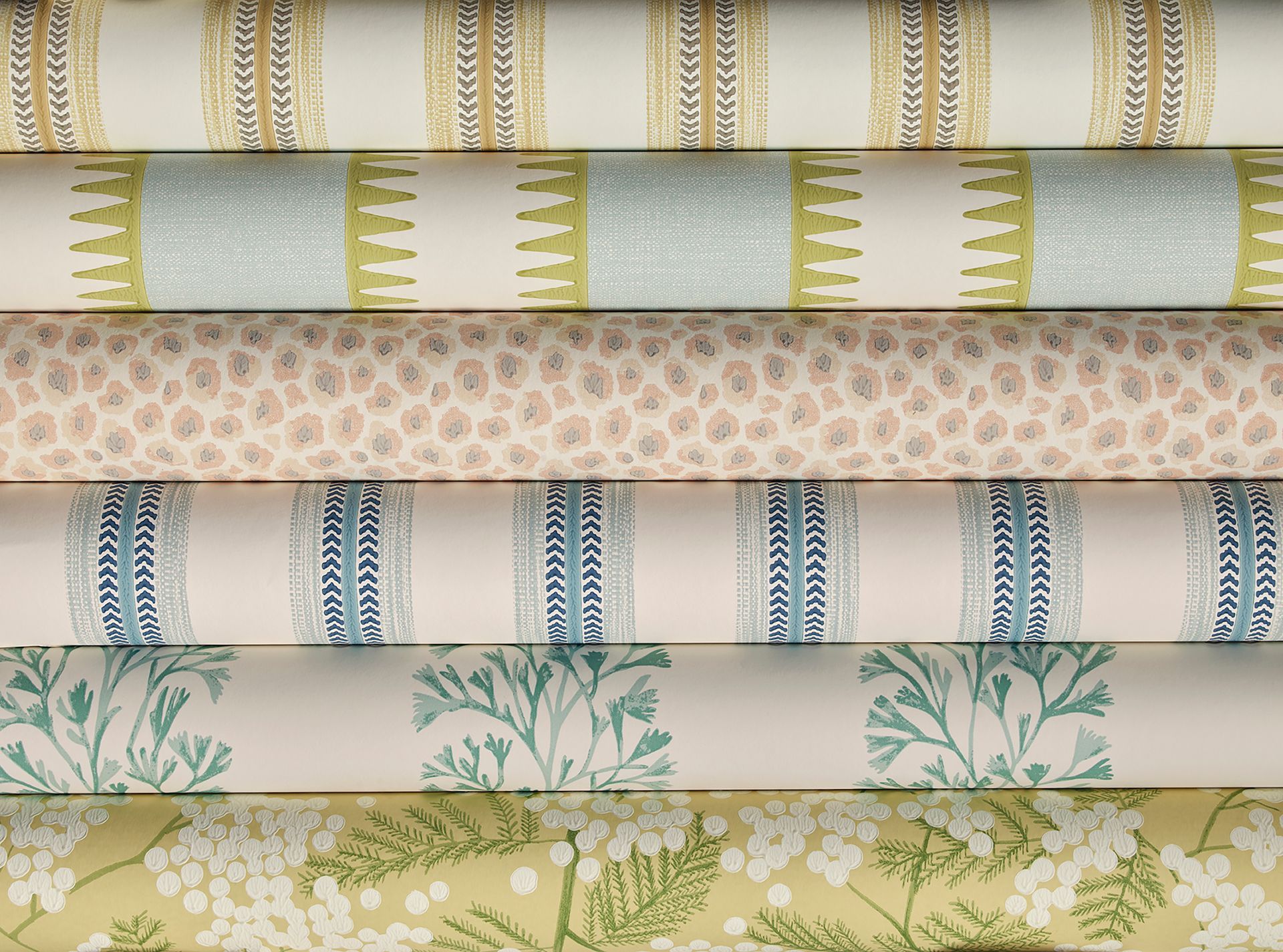 Ein Stapel Stoffrollen mit verschiedenen Mustern und Farben, darunter Streifen, Blumen und Punkte.