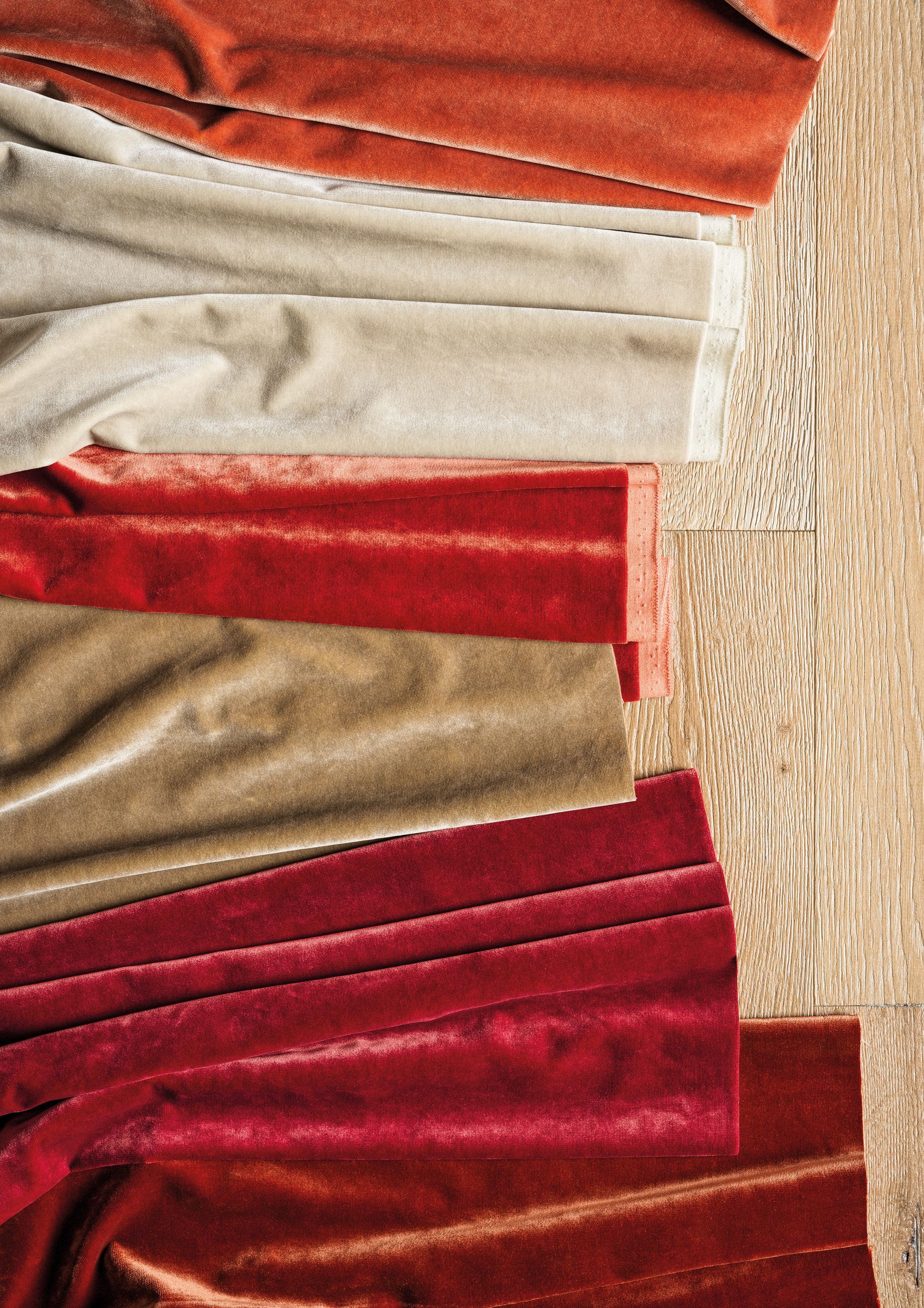 Nahaufnahme einer Sammlung von Samtstoffmustern in Rot-, Orange- und Hellbrauntönen.