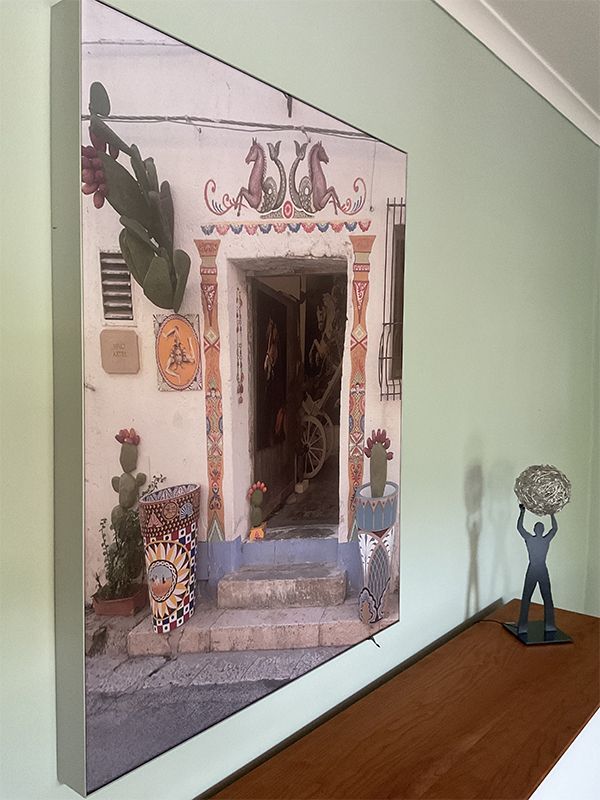 Foto eines Türrahmens mit bunten Fliesen, einem Kaktus und einer Figur auf einer Holzoberfläche vor einer grünen Wand.