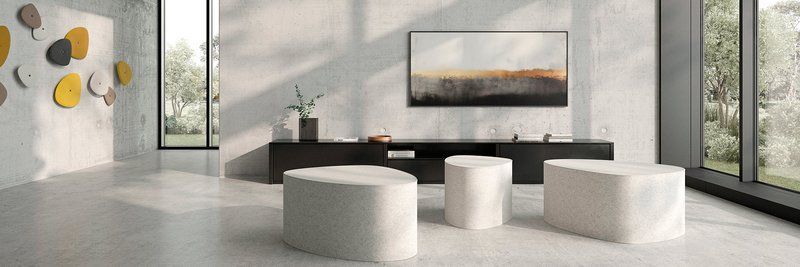 Modernes Wohnzimmer mit weißen Möbeln, dunkler Medienkonsole und großen Fenstern mit Blick auf Bäume.