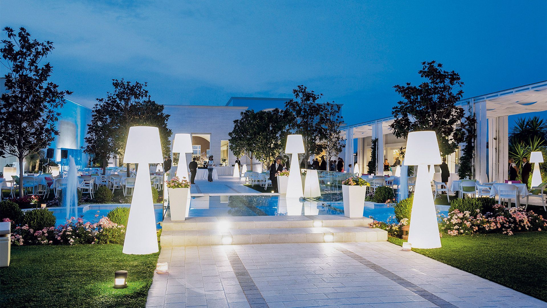 Abendveranstaltung im Freien mit beleuchteten Lampen, Gehweg und Sitzbereichen.