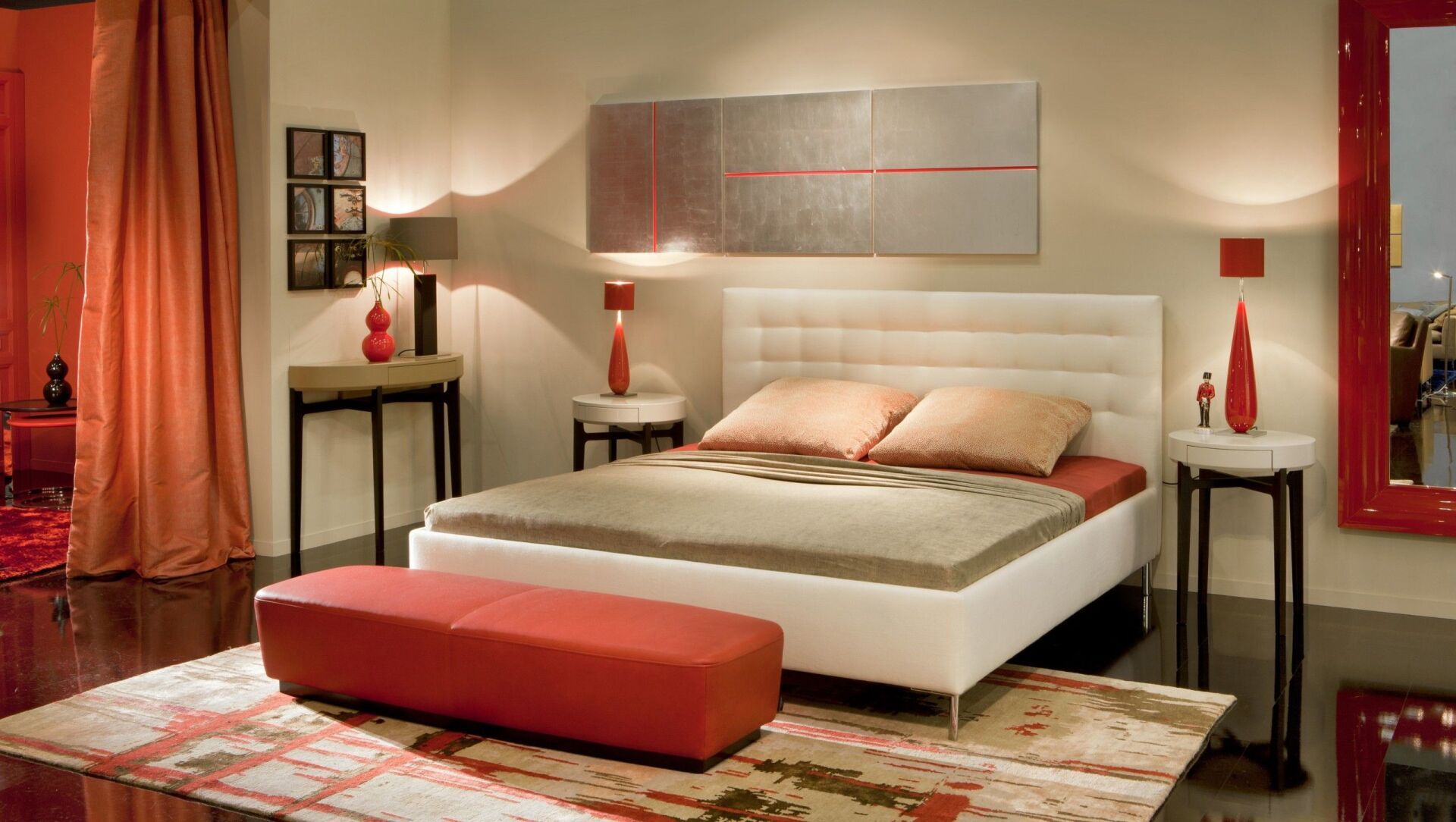 Modernes Schlafzimmer mit weißem Bett, roten Akzenten und neutralen Wänden.