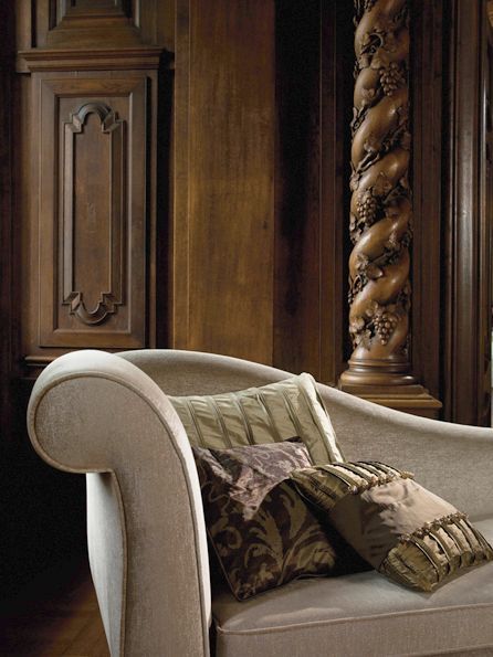 Eine Chaiselongue mit Kissen in einem Raum mit dunkler Holzvertäfelung und einer dekorativen Säule.