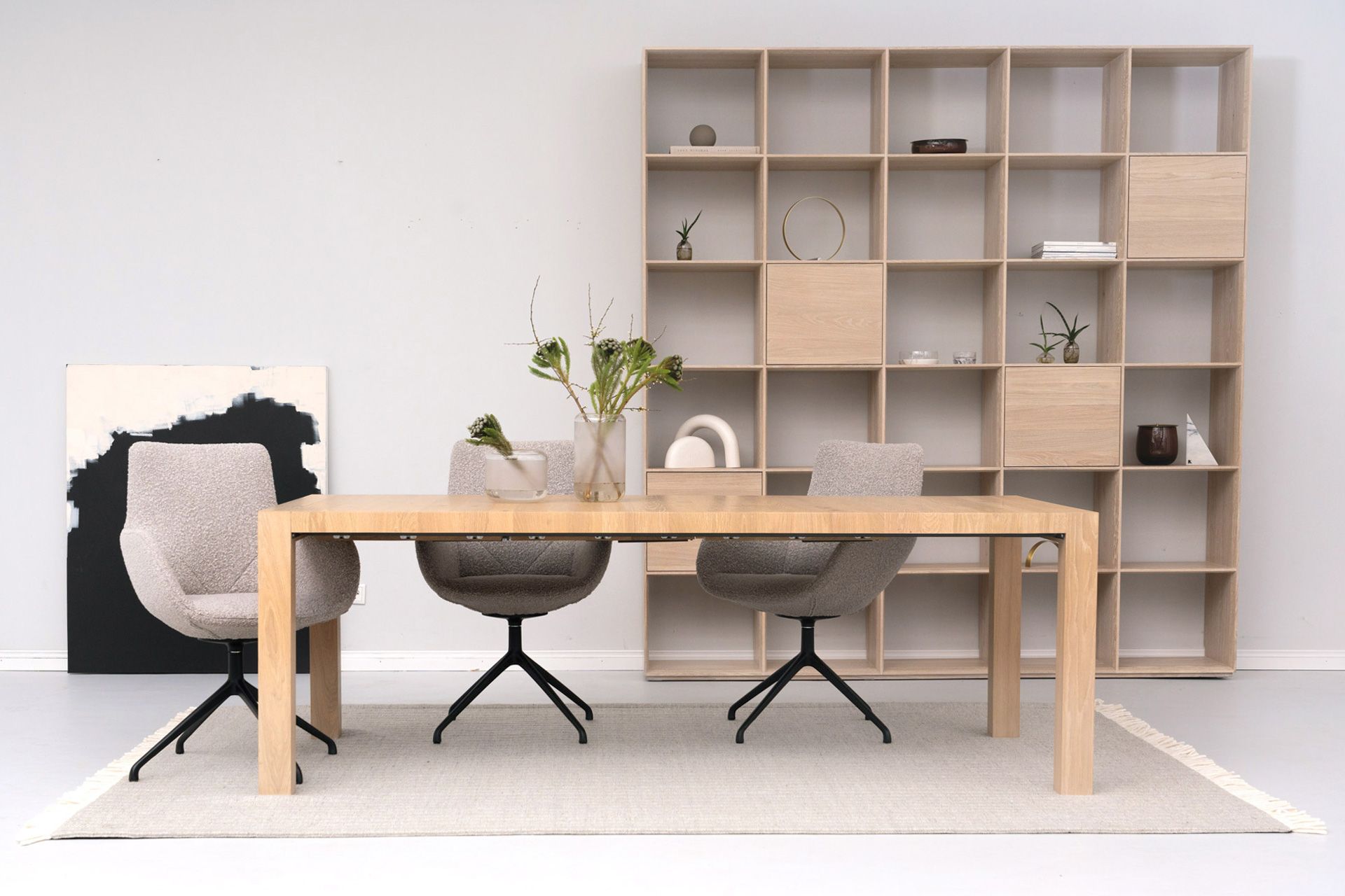 Esszimmer mit einem Holztisch, drei Stühlen und einem großen Regal.