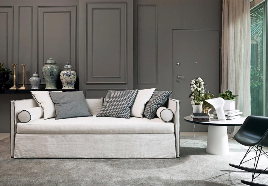 Wohnzimmer mit grauen Wänden, weißem Sofa und schwarzem Tisch.