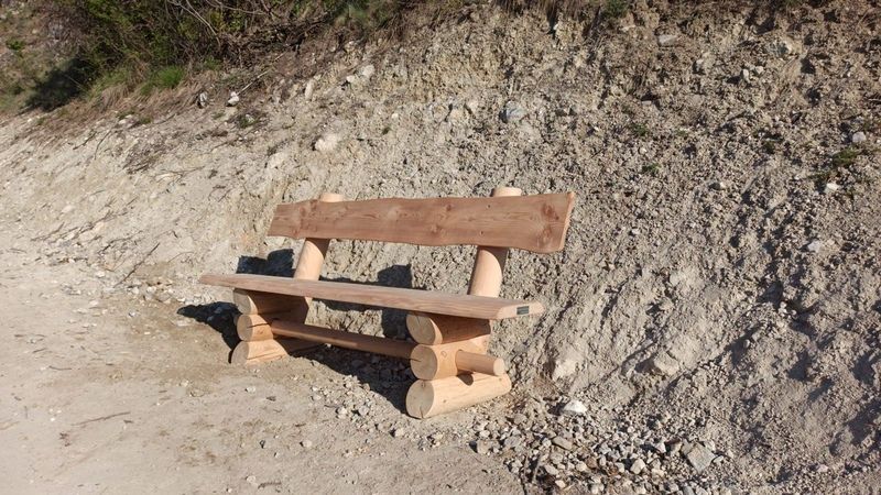 Un banc en bois est assis au bord d'un chemin de terre.