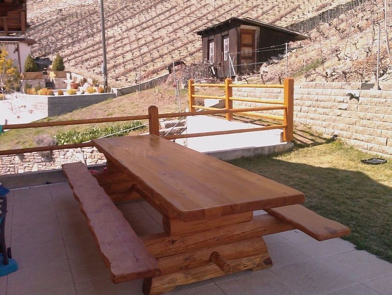 Une table de pique-nique en bois avec des bancs et une clôture en arrière-plan