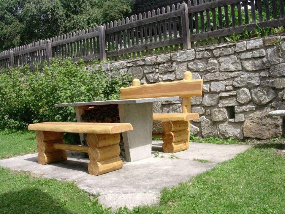 Un mur de pierre avec une table et deux bancs devant