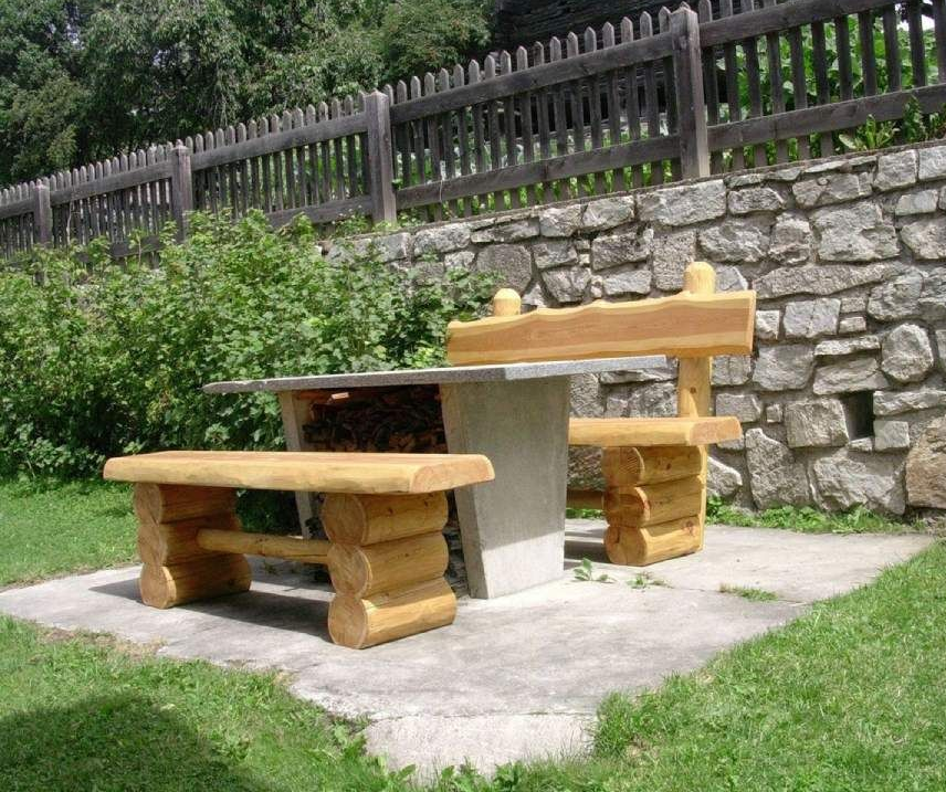 Un mur de pierre avec une table et deux bancs devant