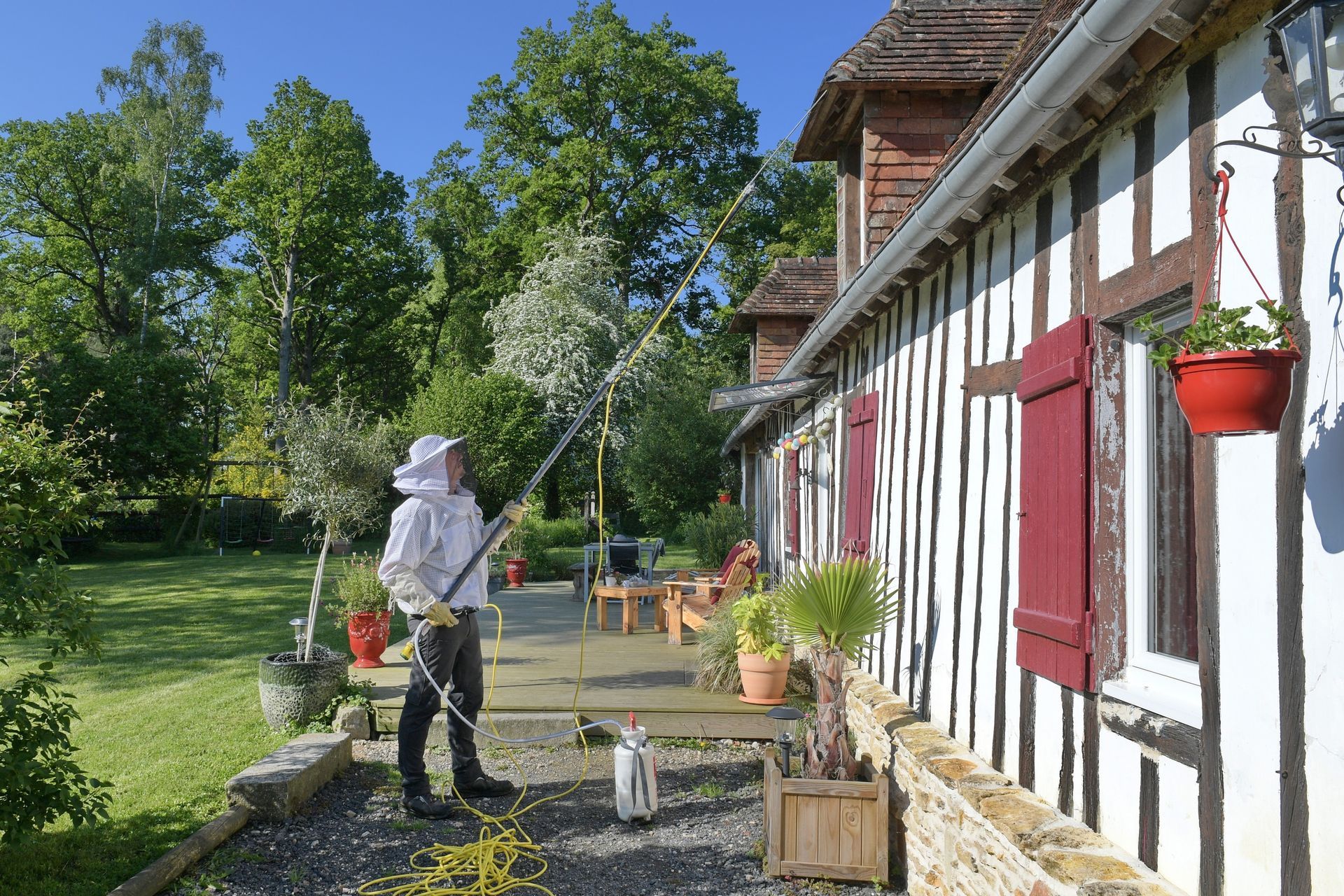 M. Croteau avec une perche pour pulvériser du produit dans un nid sous un toit