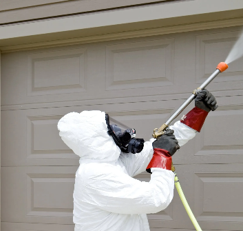 Homme en combinaison désinfectant une porte de garage