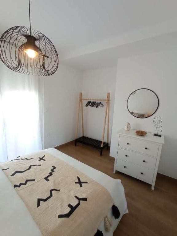 Un dormitorio con cama, cómoda, espejo y ventana.