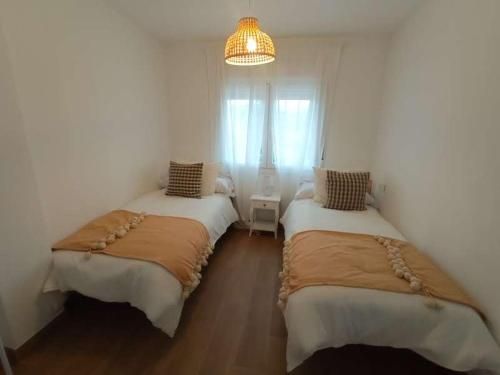 Un dormitorio con dos camas y una lámpara colgando del techo.