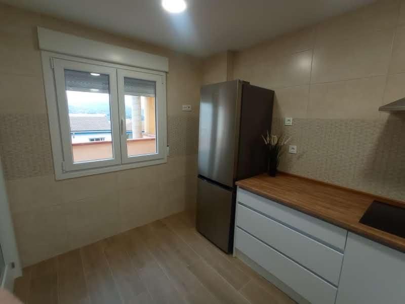 Una cocina con refrigerador de acero inoxidable y ventana.