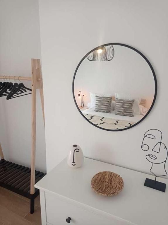 Un dormitorio con un espejo redondo en la pared encima de una cómoda.