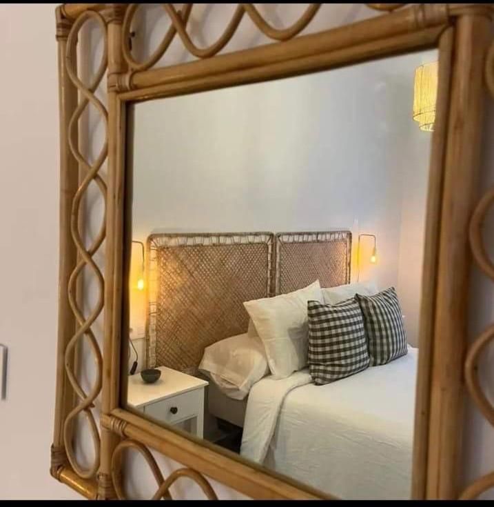 Un dormitorio con una cama y un espejo con marco de mimbre.