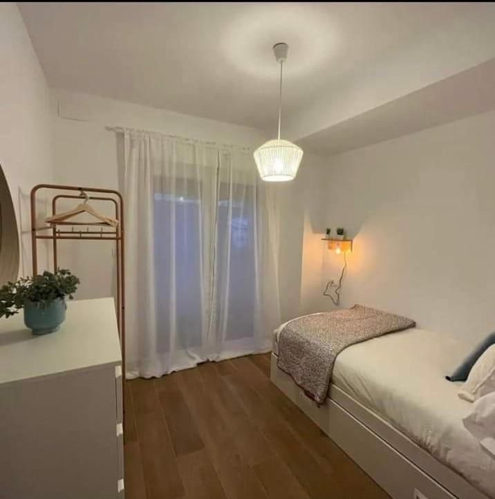 Un dormitorio con una cama individual, cómoda, espejo y ventana.