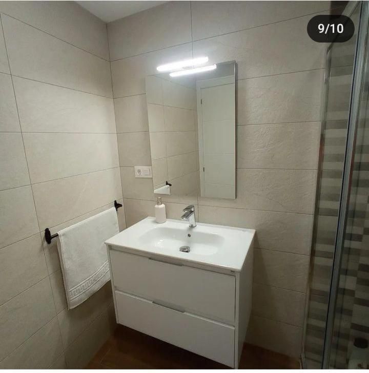 Un baño con lavabo, espejo y toallero.