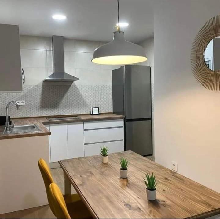 Una cocina con mesa y sillas de madera y un refrigerador de acero inoxidable.