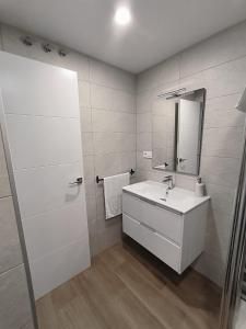 Un baño con lavabo, espejo y toallero.