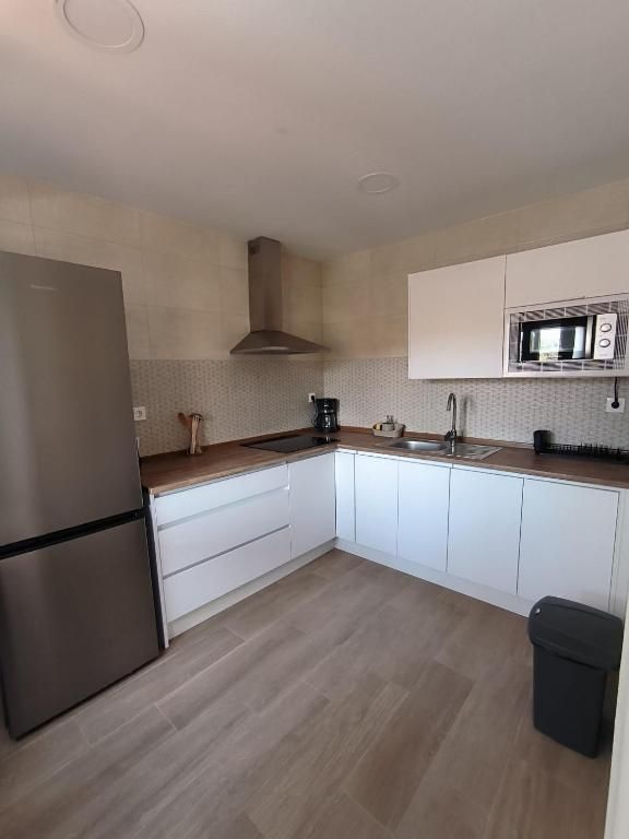 Una cocina con gabinetes blancos y un refrigerador de acero inoxidable.