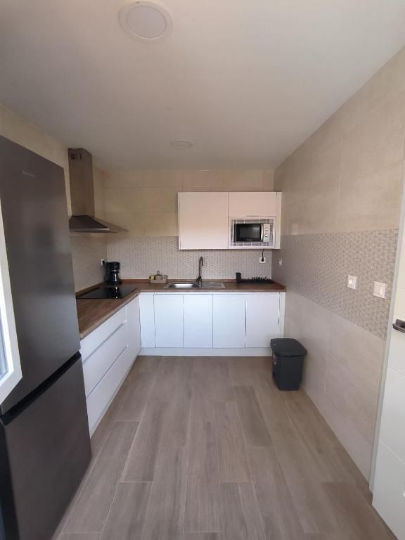 Una cocina con gabinetes blancos y un refrigerador negro.