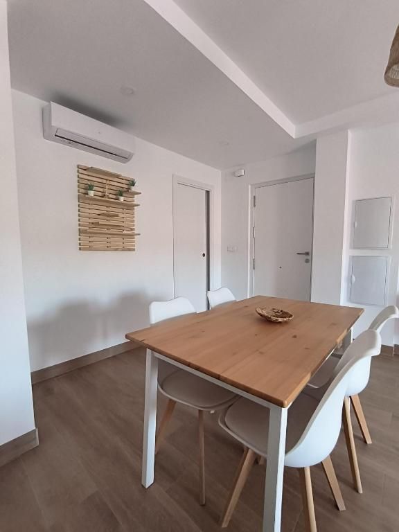 Un comedor con una mesa de madera y sillas blancas.